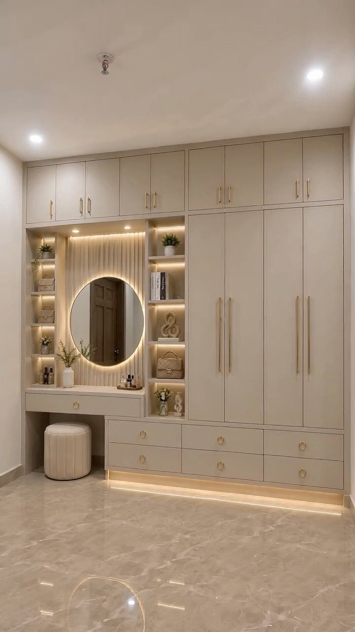 Built-in beige wardrobe and vanity unit with a circular backlit mirror in a bedroom.
