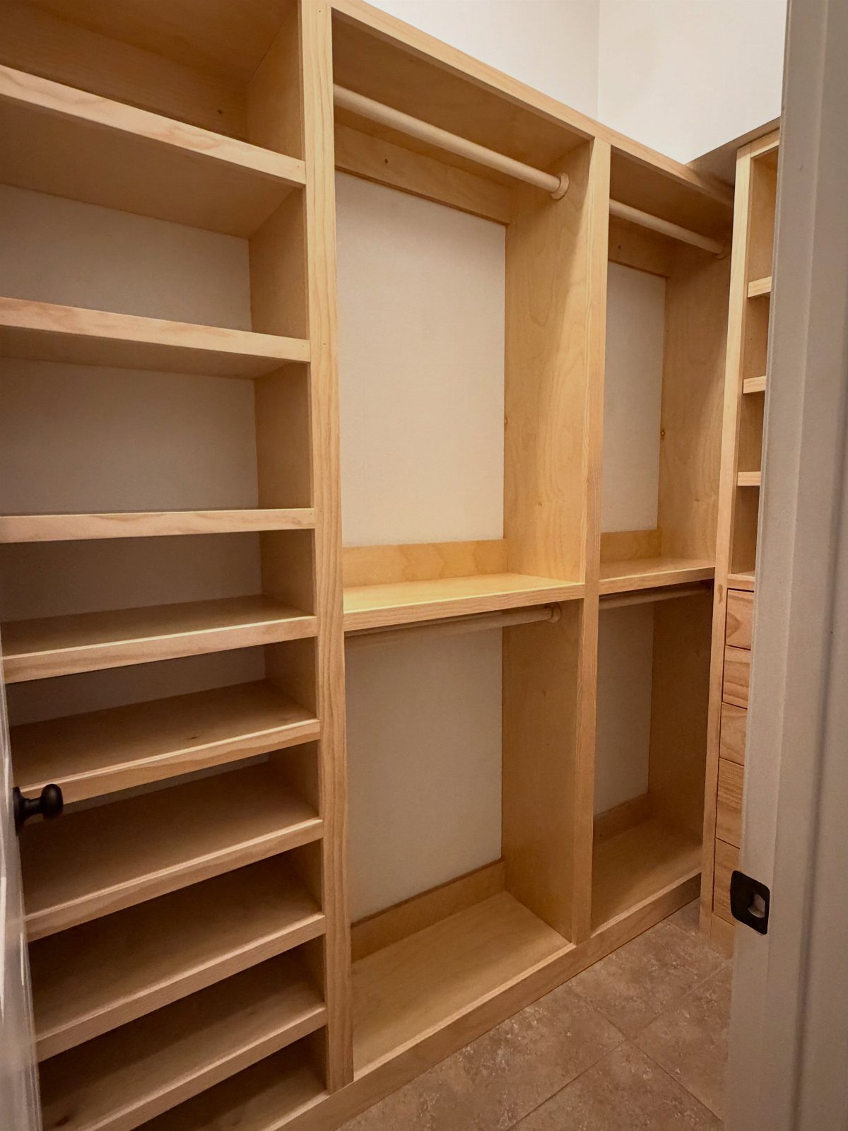 Hardwood plywood closet system with open shelves and hanging rods in a room.