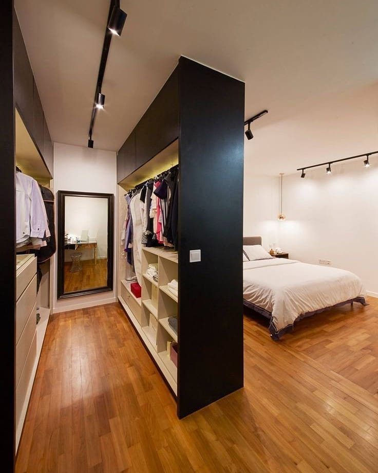 Black built-in open closet partition separating a bedroom sleeping area from a dressing space.