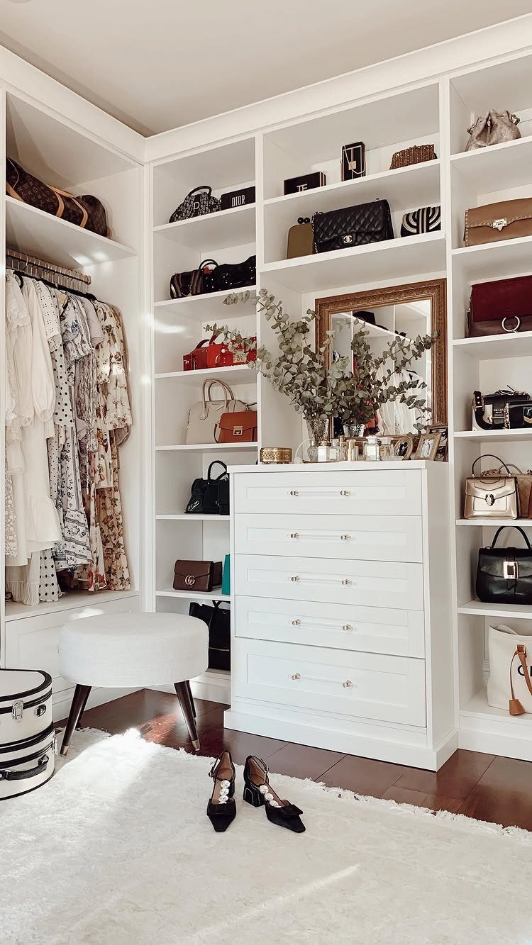 White built-in walk-in closet with shelving, dresser, and hanging clothes on wood floor