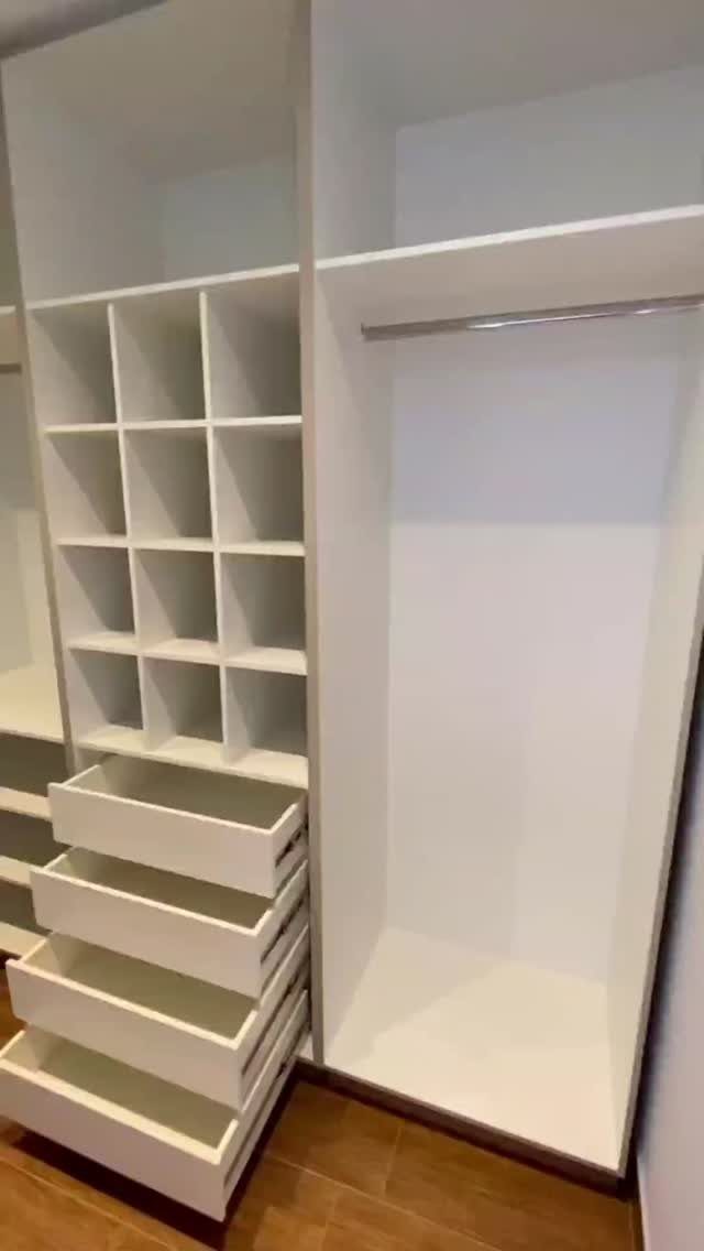 White built-in closet system with open cubbies, drawers, and a hanging rod.