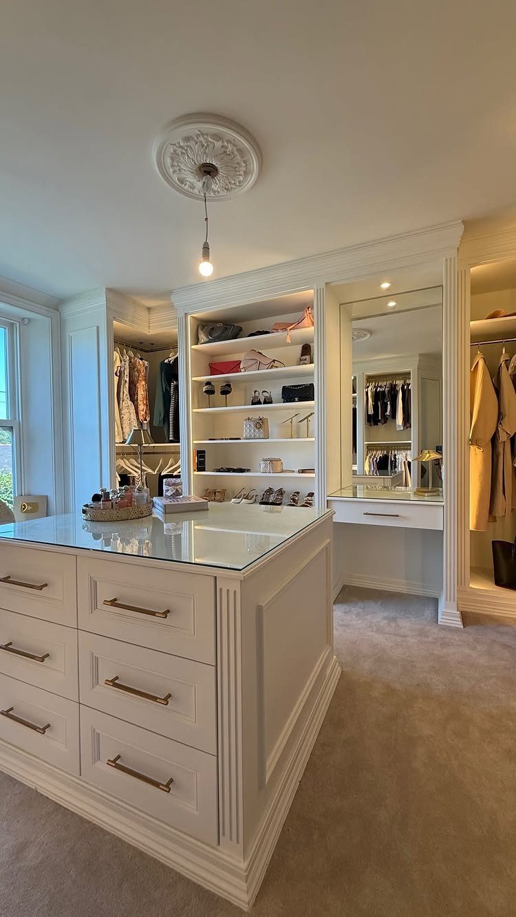 White walk-in closet with a central island and a built-in vanity mirror.
