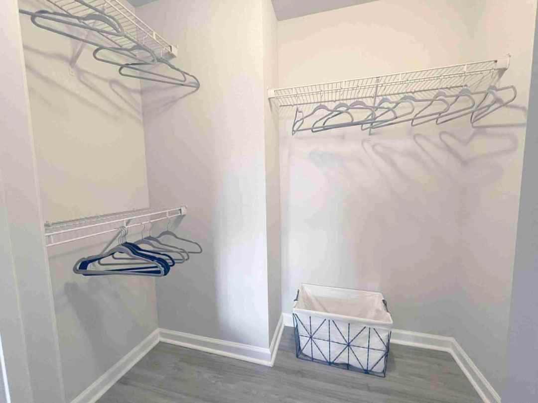 White wire hanging rods with blue hangers in a bright walk-in closet
