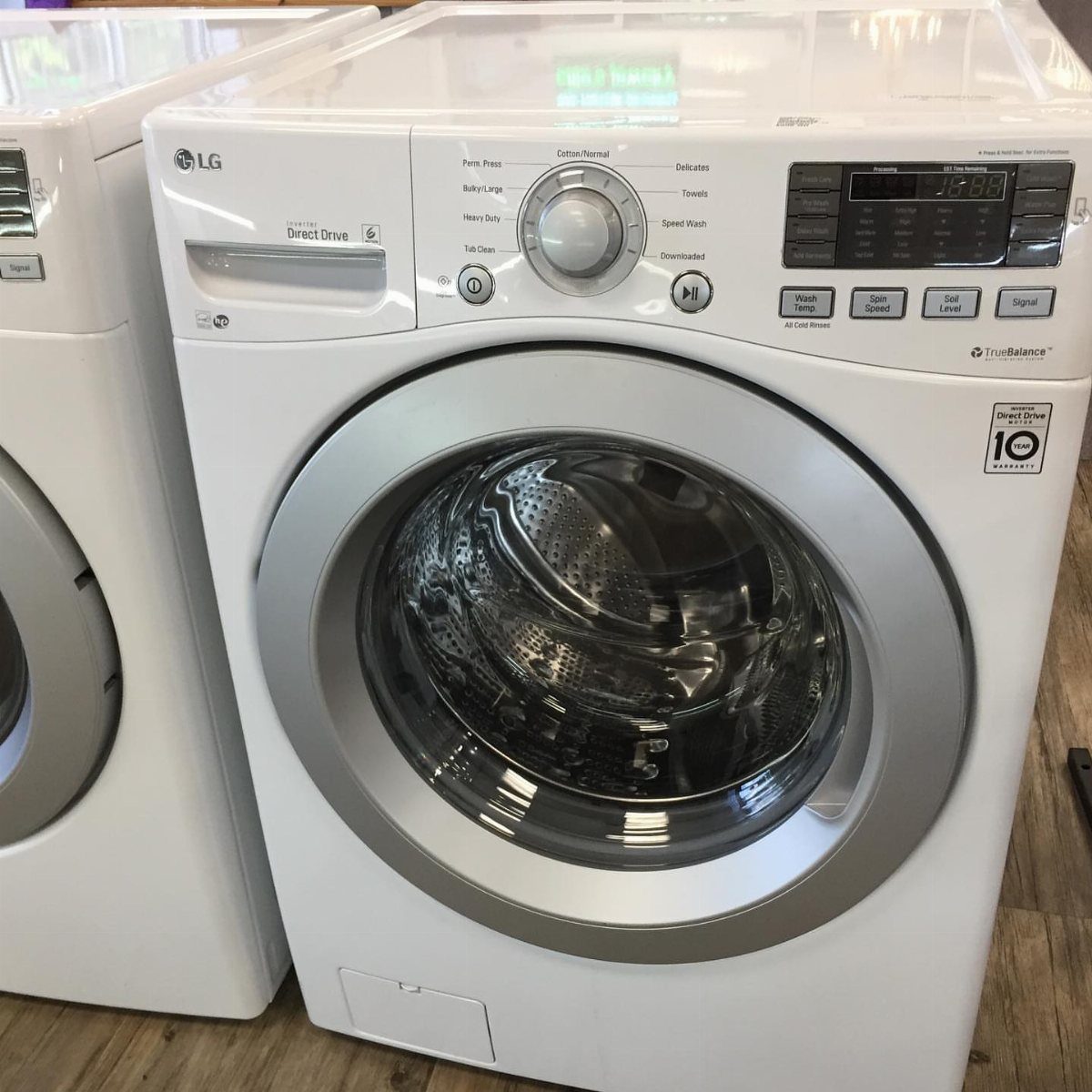 White LG front-loading washer and dryer set on a light wooden floor.
