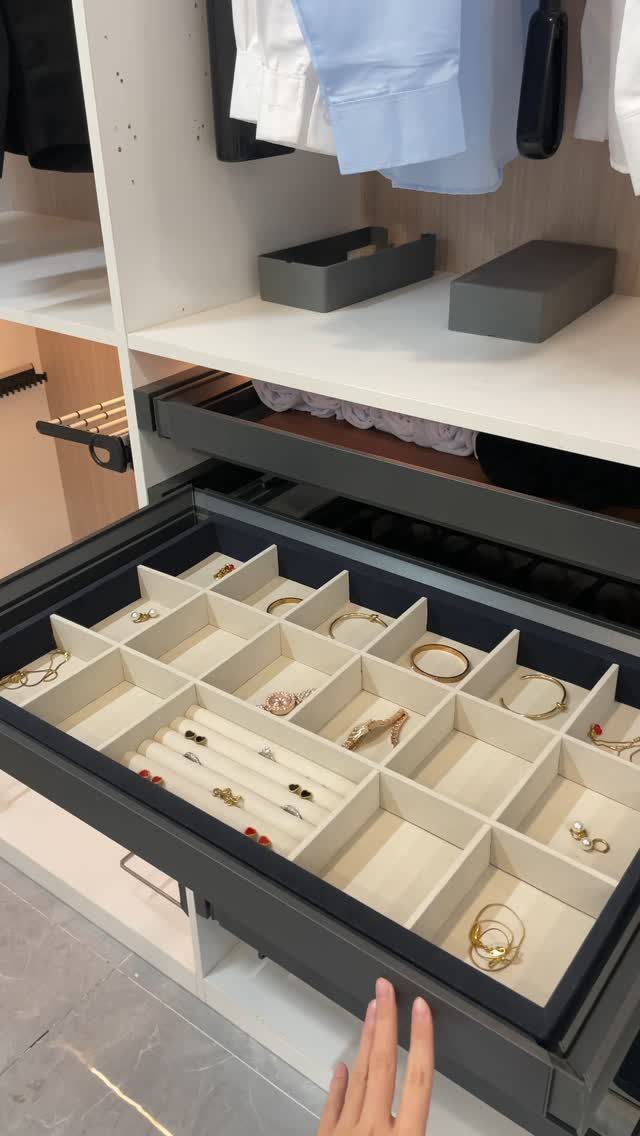 Jewelry organizer drawer with gold rings and bracelets in a white closet system