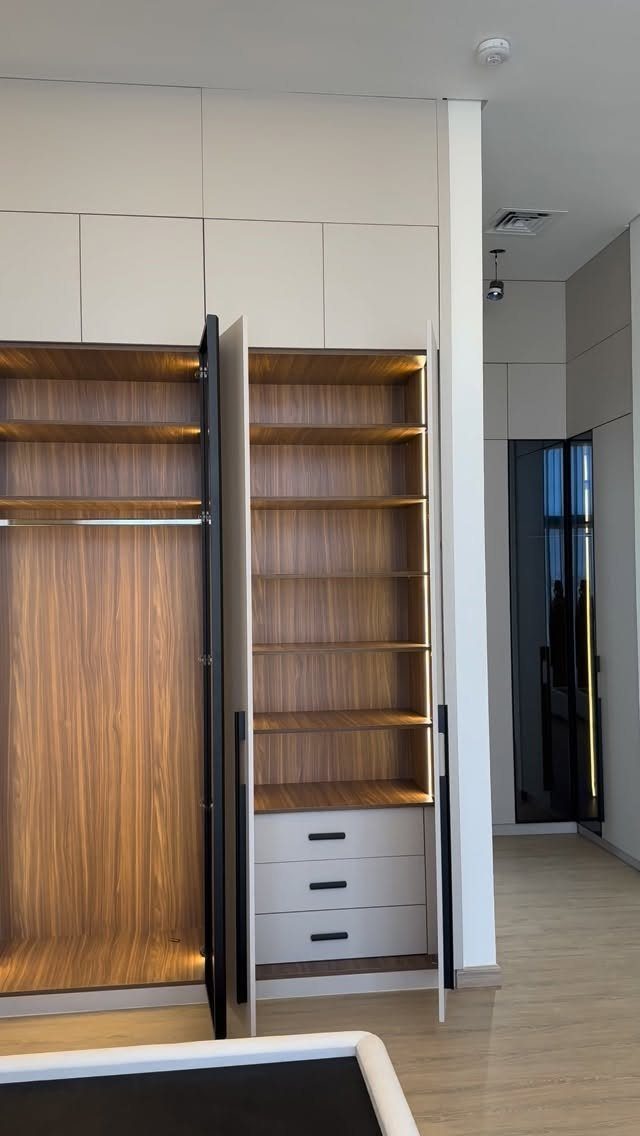 Modern built-in closet with wood shelving and three white storage drawers at the bottom.