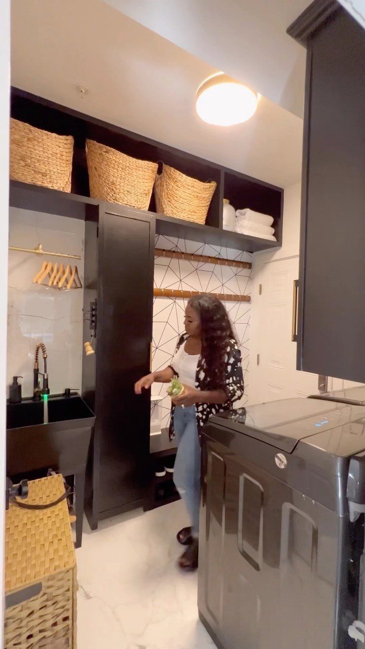 Black cabinets and laundry appliances in a modern white laundry room with baskets.