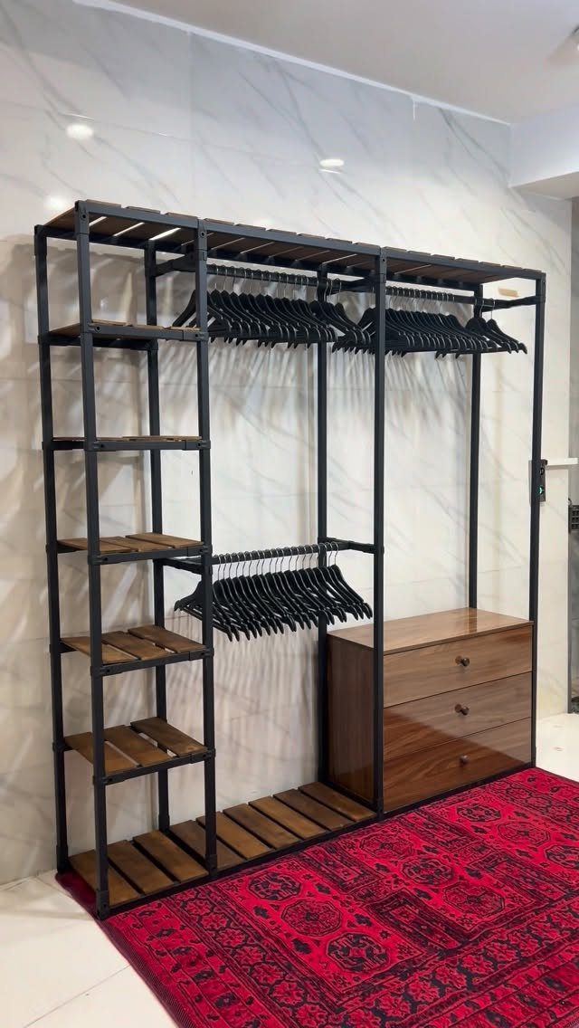 Black metal and wood closet system with hanging rods and a wooden dresser.