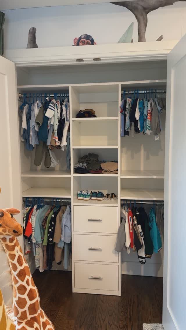 White built-in closet system with hanging rods, shelves, and drawers for children's clothes.