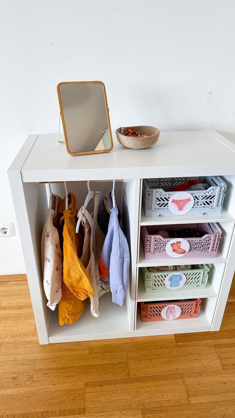 White modular shelving unit organized as a closet with hanging clothes and bins.