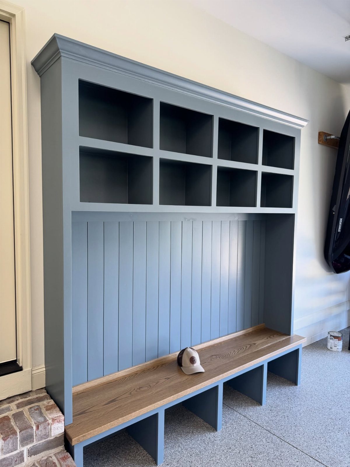 Blue built-in mudroom bench with wooden seat and open storage cubbies above.