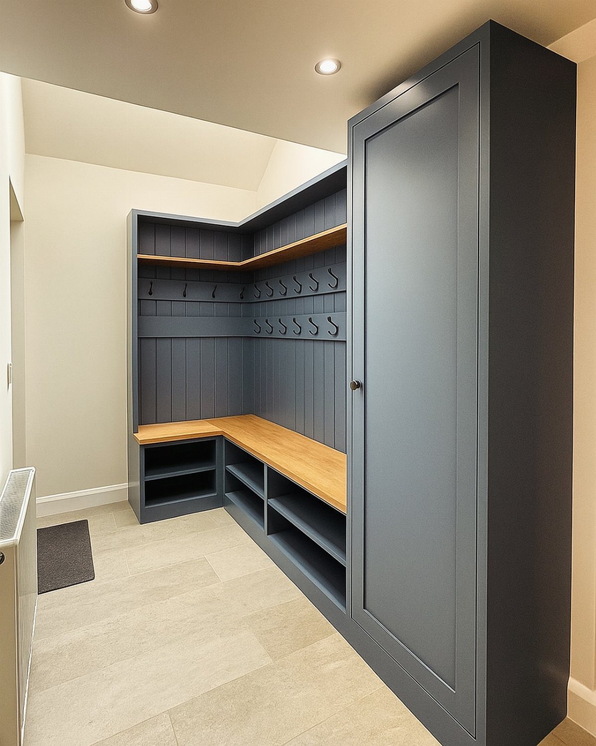 L-shaped corner mudroom bench with wood seat, grey paneling, and black hooks.