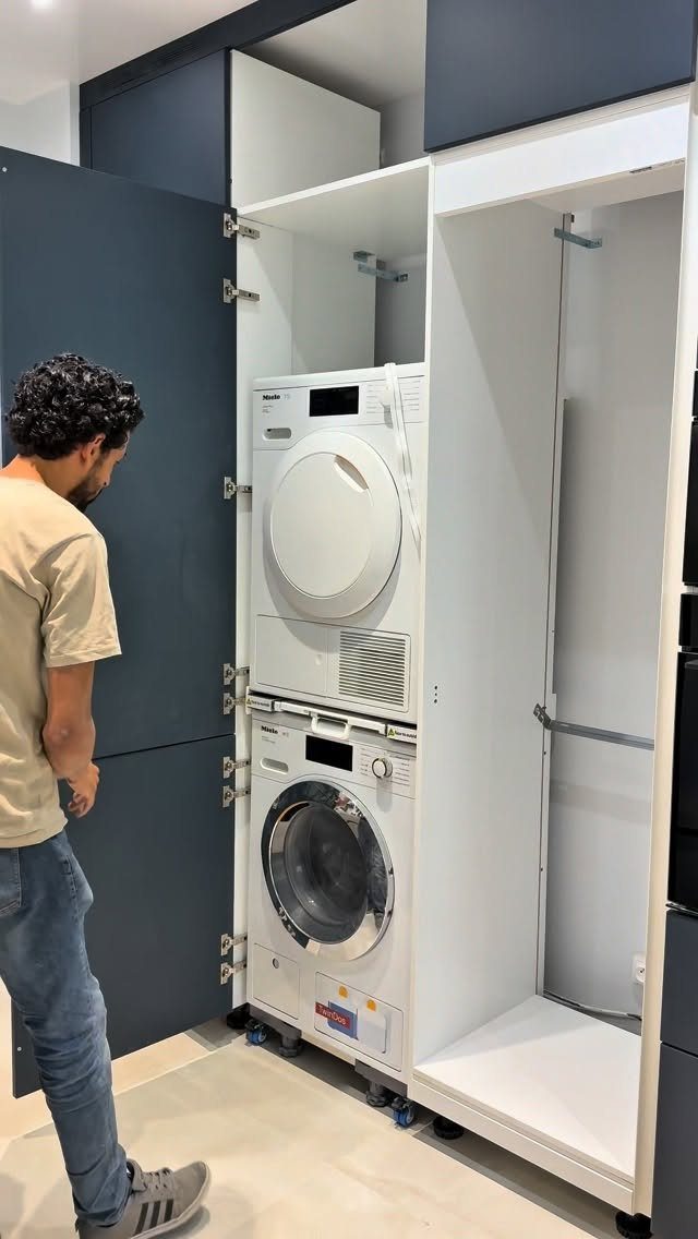 Stacked washer and dryer installed inside a white and dark blue built-in cabinet.