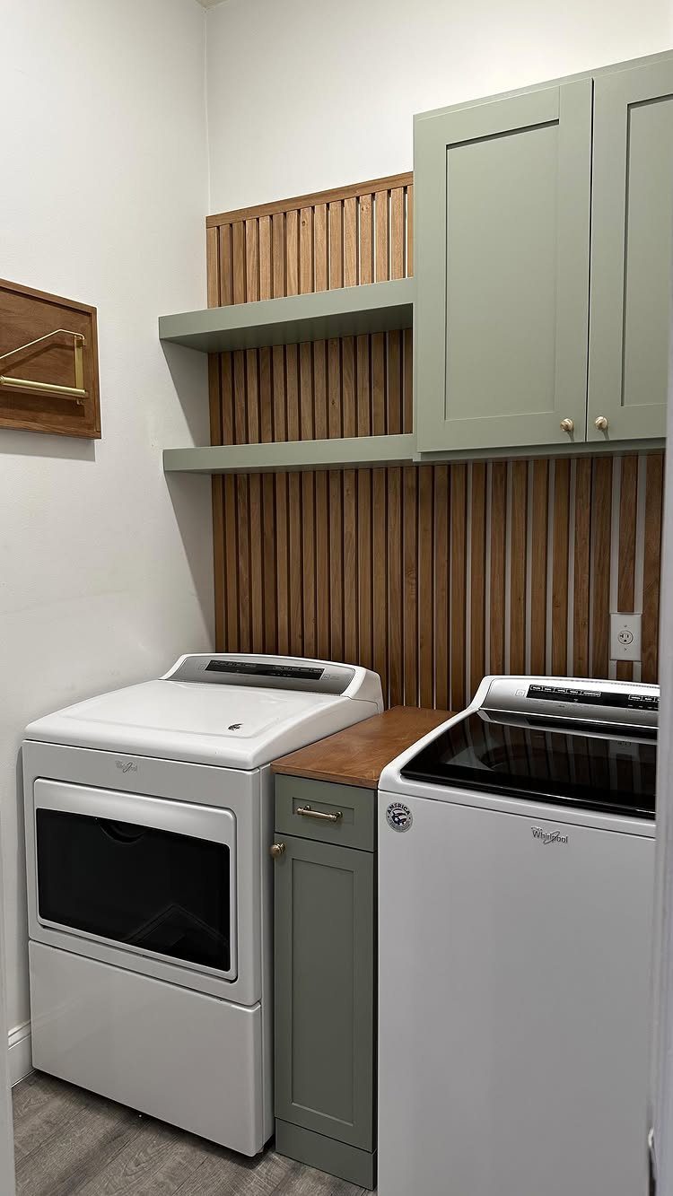 Sage green wall-mounted shelves and cabinets above a white washer and dryer set.