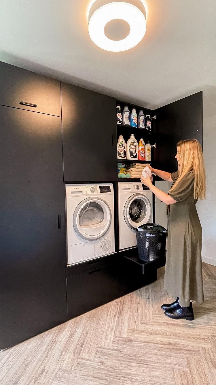 Black cabinets installed over a white washer and dryer in a modern laundry room.
