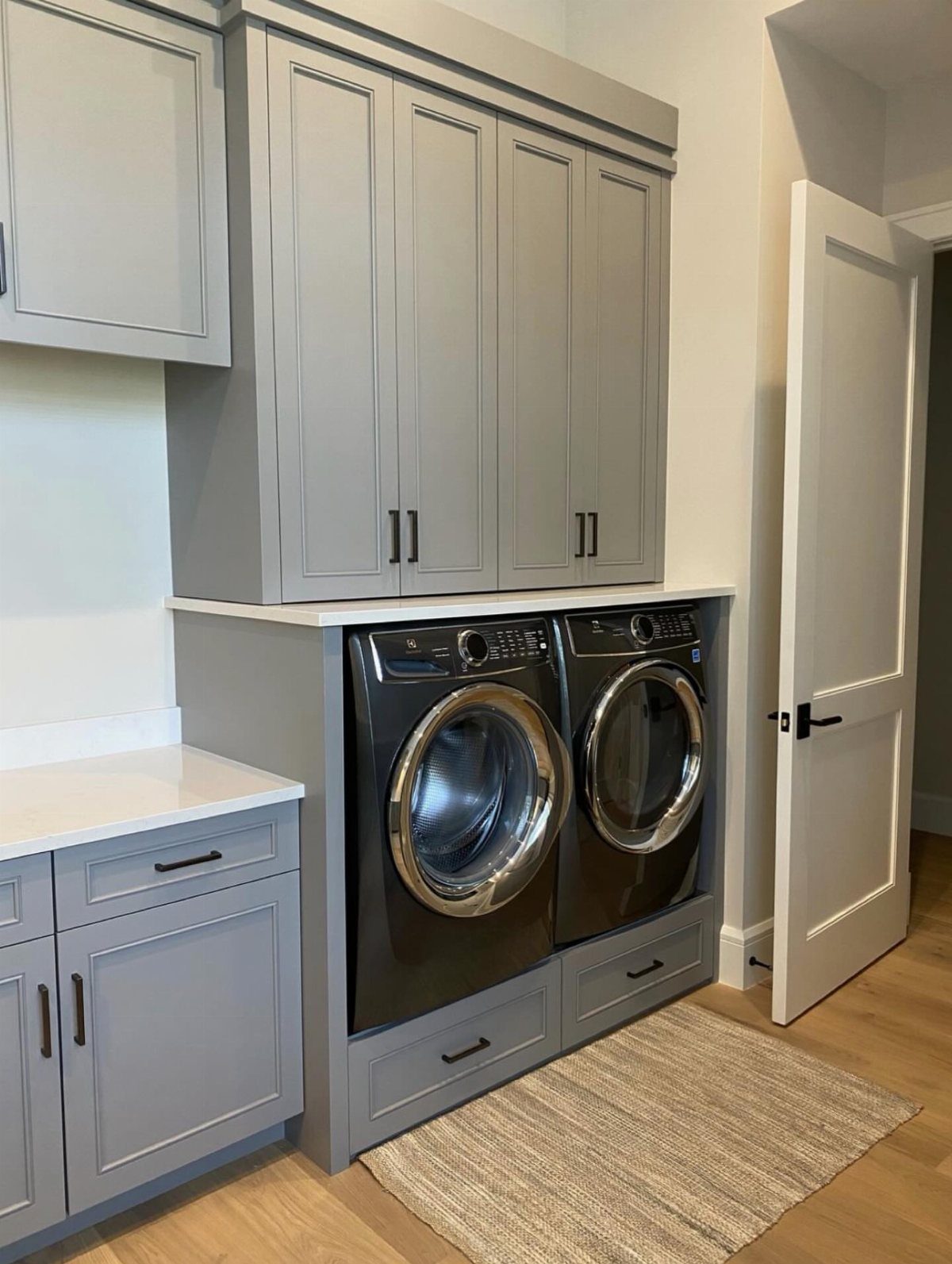 Grey cabinets installed above a black washer and dryer in a laundry room.