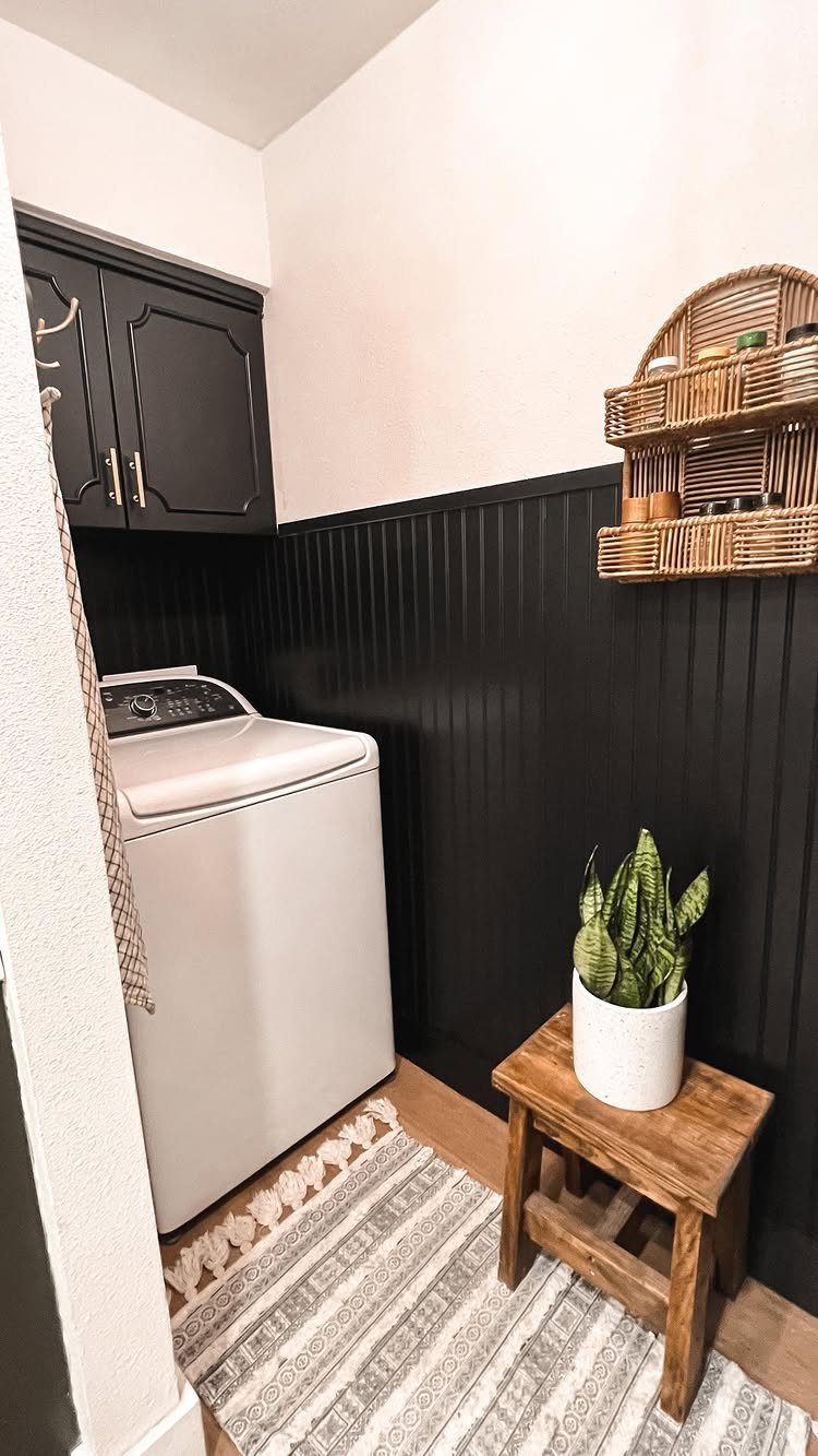 Dark grey kitchen cabinets installed over a white washing machine in a laundry room.