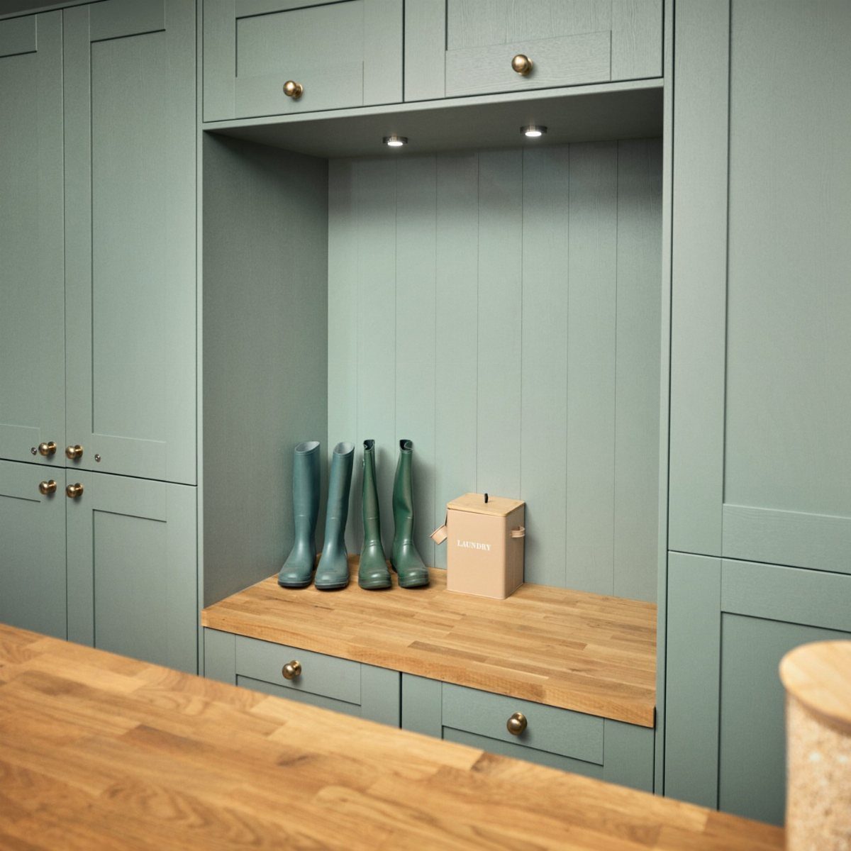 Light blue utility room with wooden bench, storage drawers, and green rain boots.