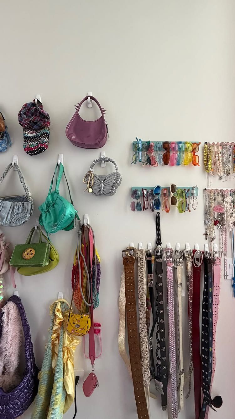 Colorful handbags, scarves, and sunglasses organized on a white wall using hooks and racks.