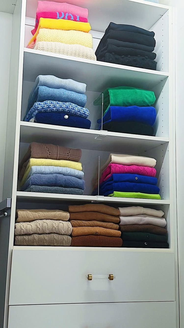 White closet shelves with neatly folded colorful sweaters and shirts stacked organizedly.