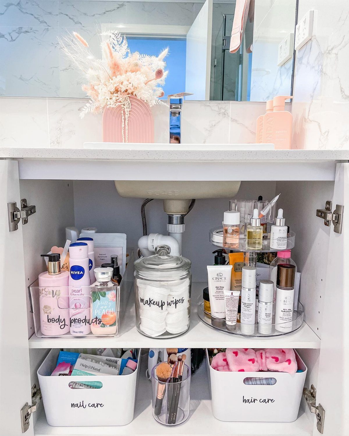 Bathroom vanity cabinet with organized bins and a rotating lazy susan for skincare bottles.