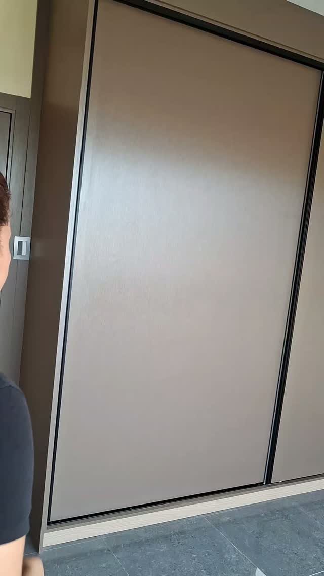 Grey sliding door wardrobe built into a room with a slanted ceiling.
