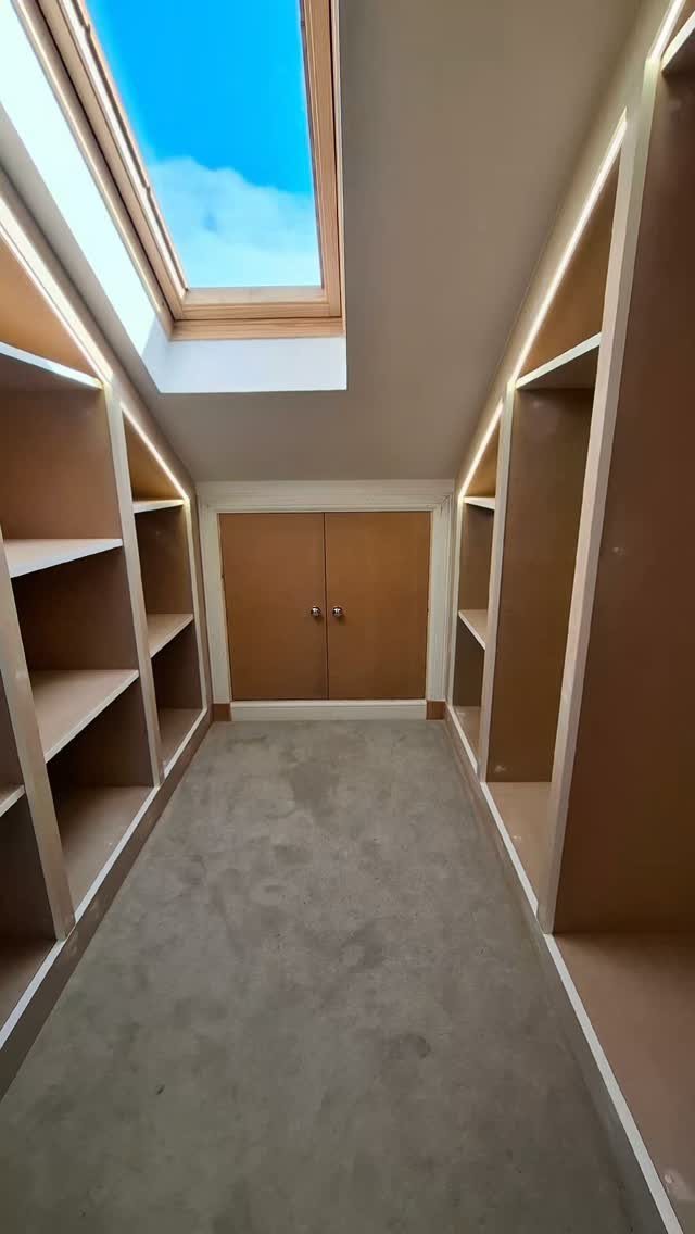 Built-in custom shelves following the slope of a slanted ceiling in a closet.