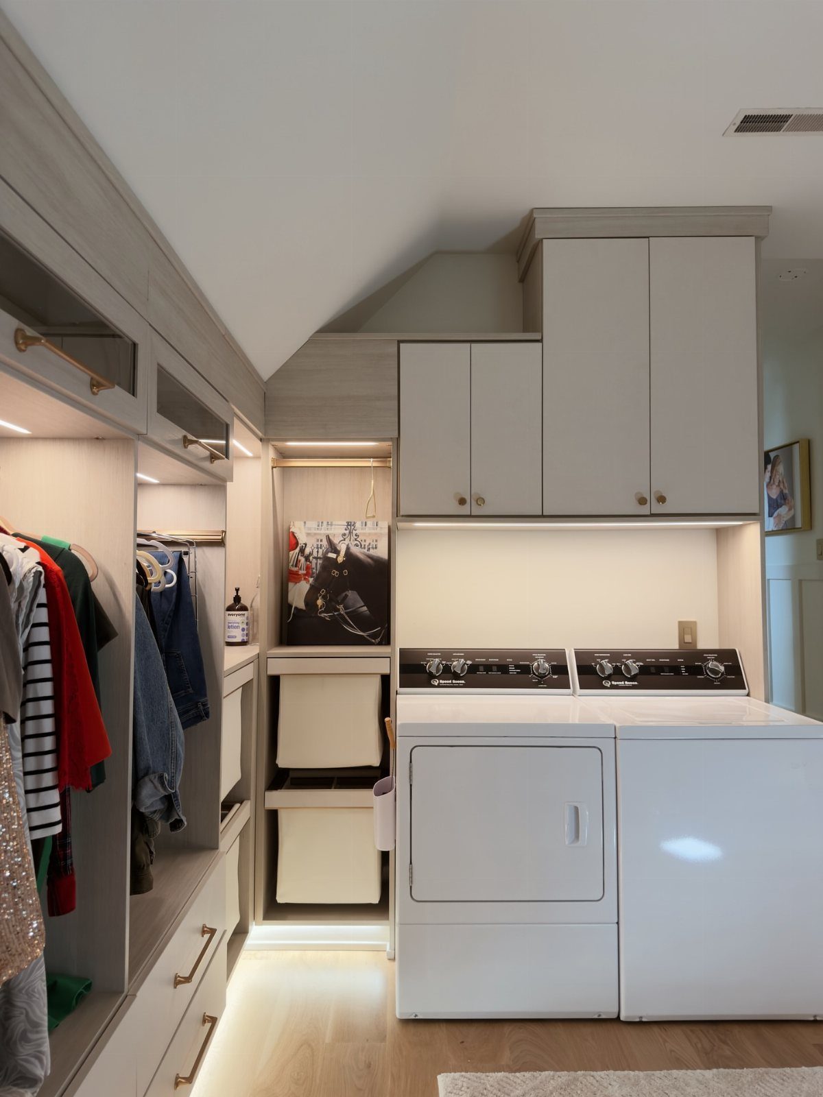 Laundry room and closet with slanted ceiling, white cabinets, and pull-out storage bins.