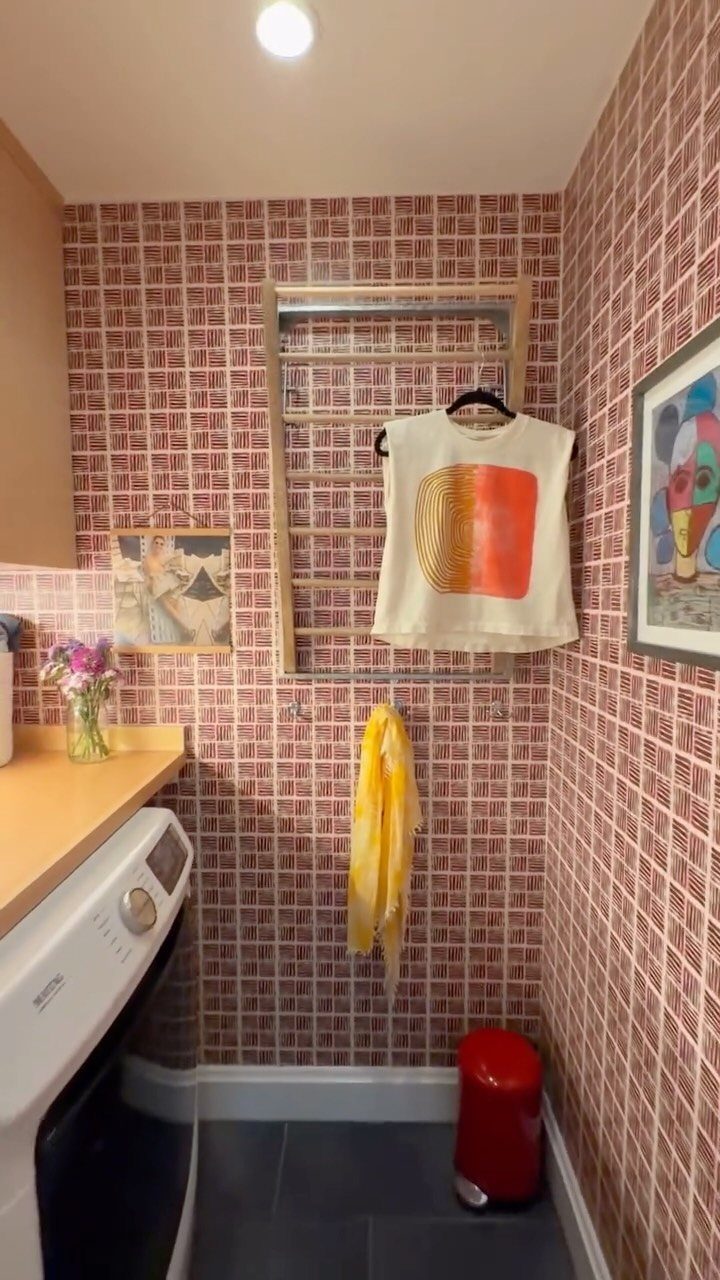 Red and white grid wallpaper in a laundry room with a drying rack.