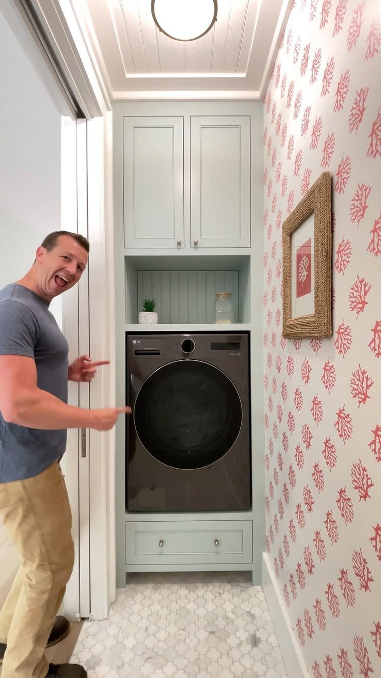 Man pointing to a compact washer-dryer combo built into light blue laundry cabinetry.