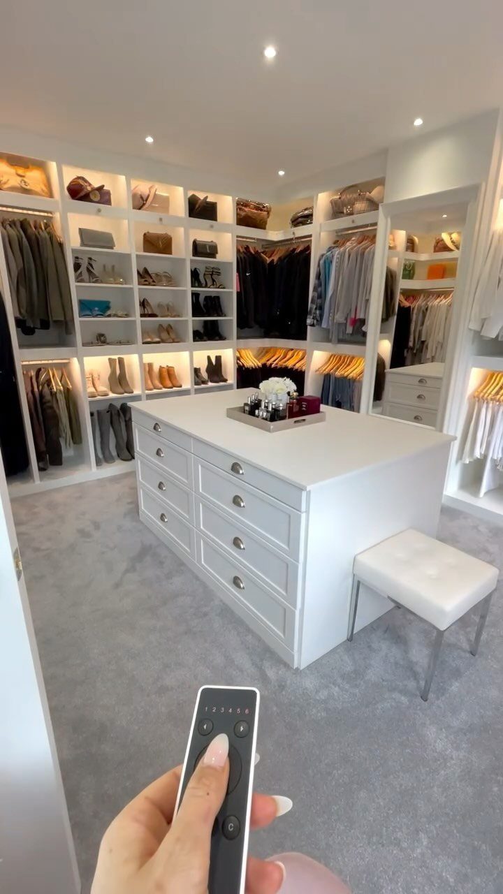 White walk-in closet with a central island and integrated LED shelf lighting.