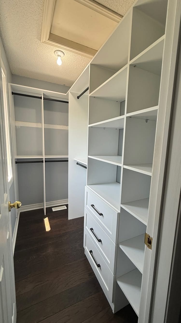 White built-in open shelves and hanging rods in a contemporary walk-in closet.