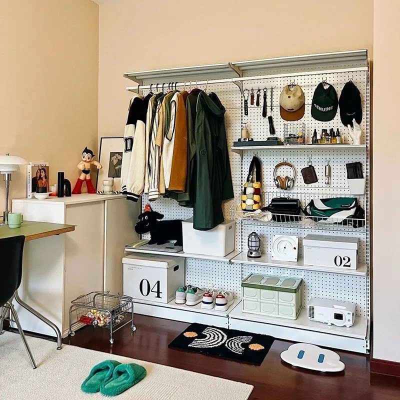 White open closet system with a pegboard organizing hats, headphones, and accessories.
