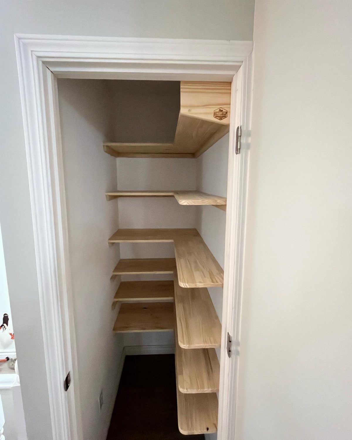 Narrow deep closet featuring light wood L-shaped shelving installed along the interior walls.