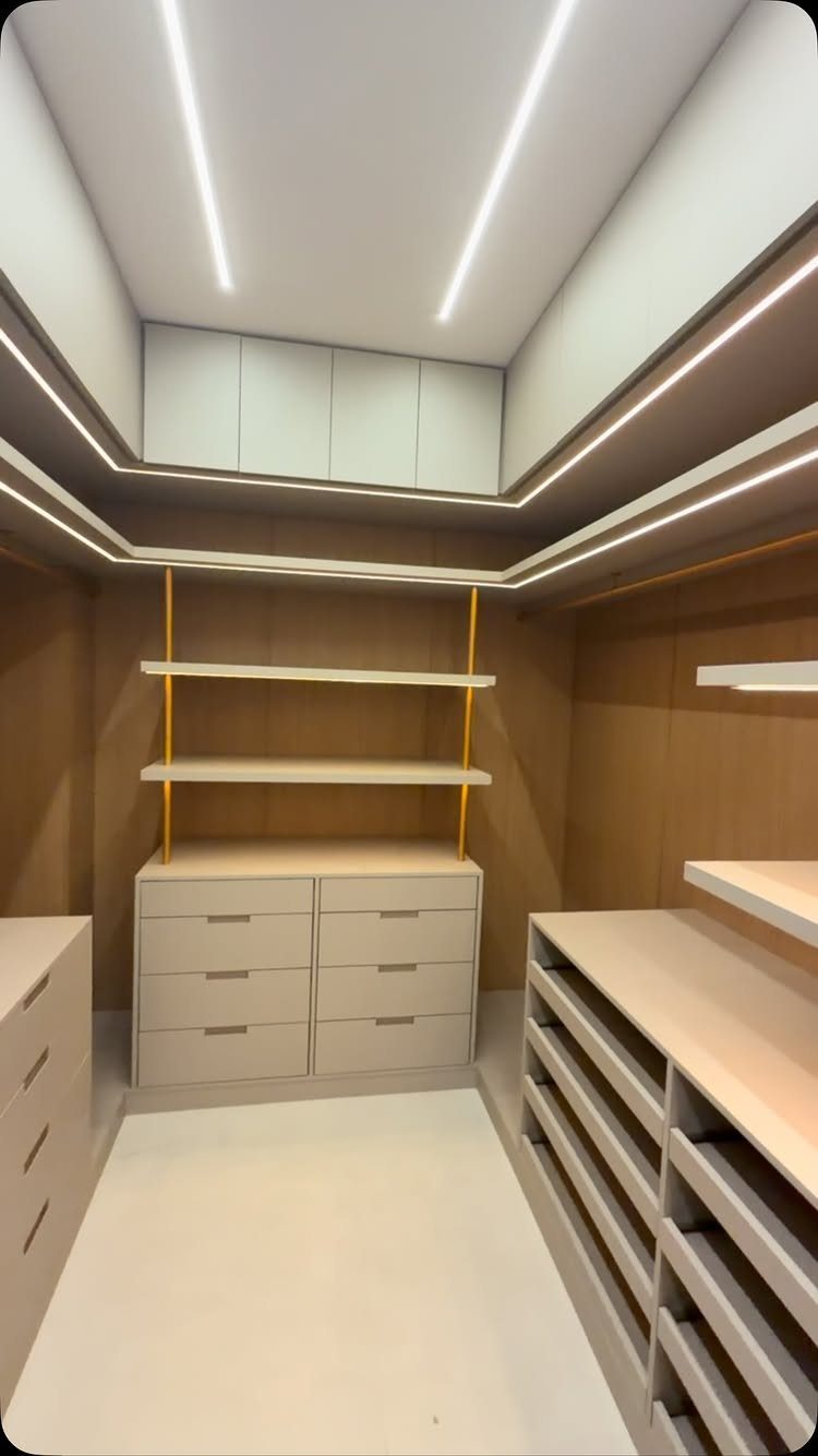 Modern narrow walk-in closet featuring integrated LED strip lighting in the ceiling and shelves.