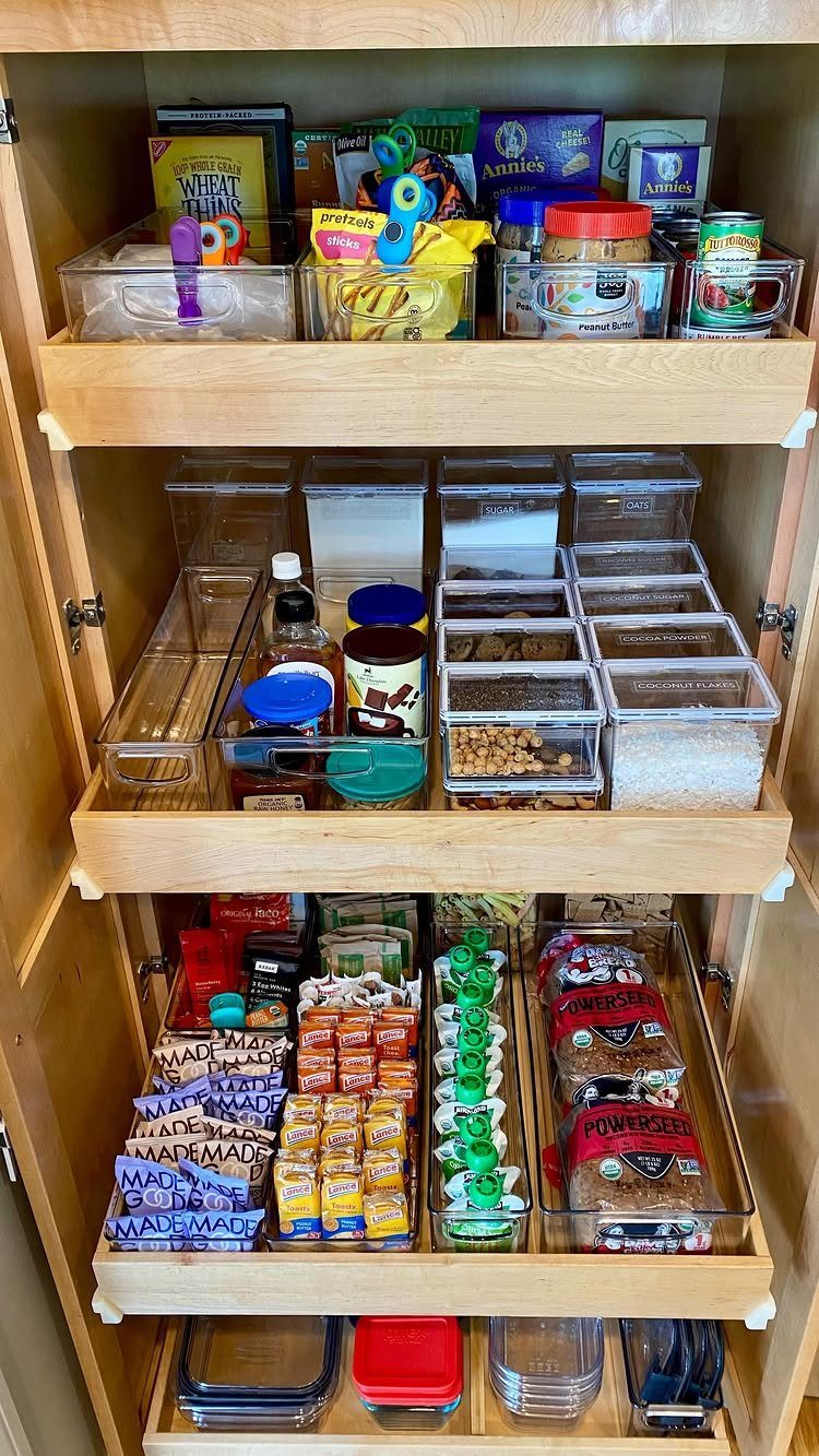 Wooden pantry shelves with food items organized in clear plastic storage bins.