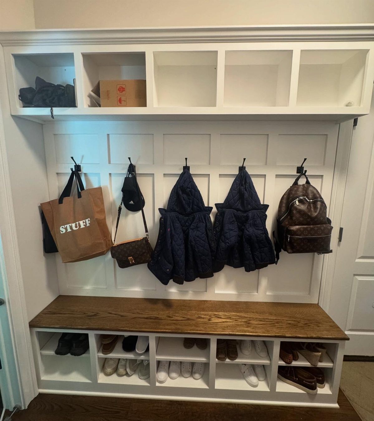 White built-in hall tree with wooden bench, upper cubbies, and shoe storage below.