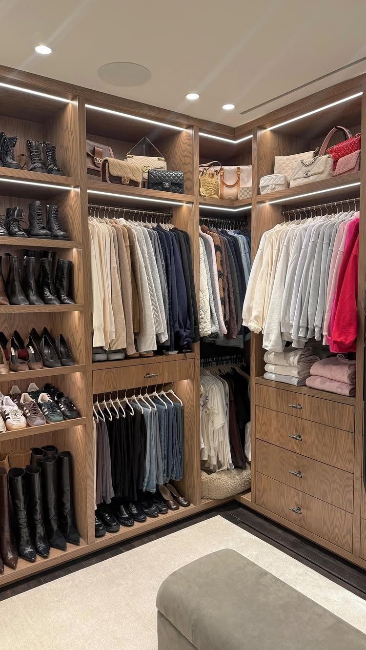 Walk-in wooden closet with LED lighting, hanging clothes, and shoe shelving.