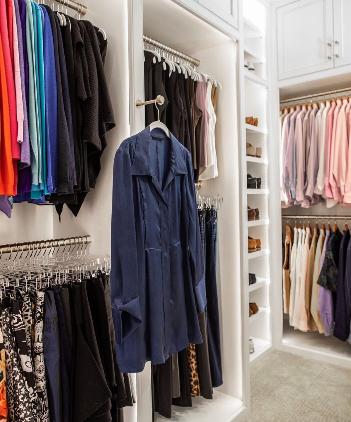 Navy blue garment hanging on a retractable valet rod in a white closet.
