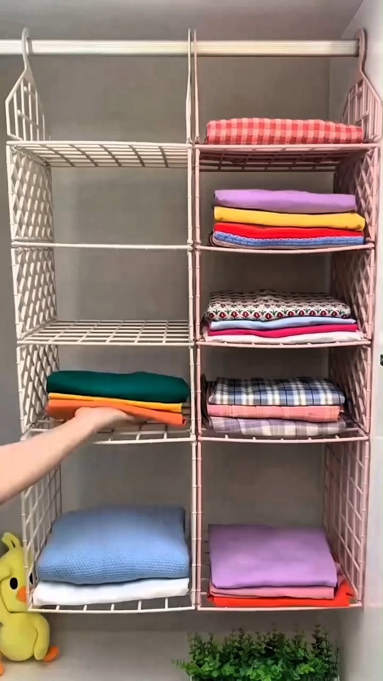 Wire grid shelving unit in a closet holding folded colorful clothing and blankets.