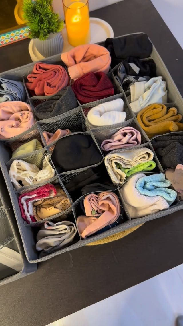 Grey fabric organizer bin with neatly folded colorful clothes in small compartments
