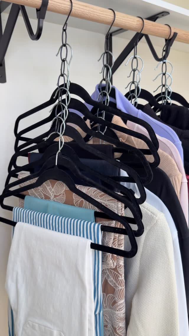 Clothes on black velvet hangers hanging from a wooden closet rod