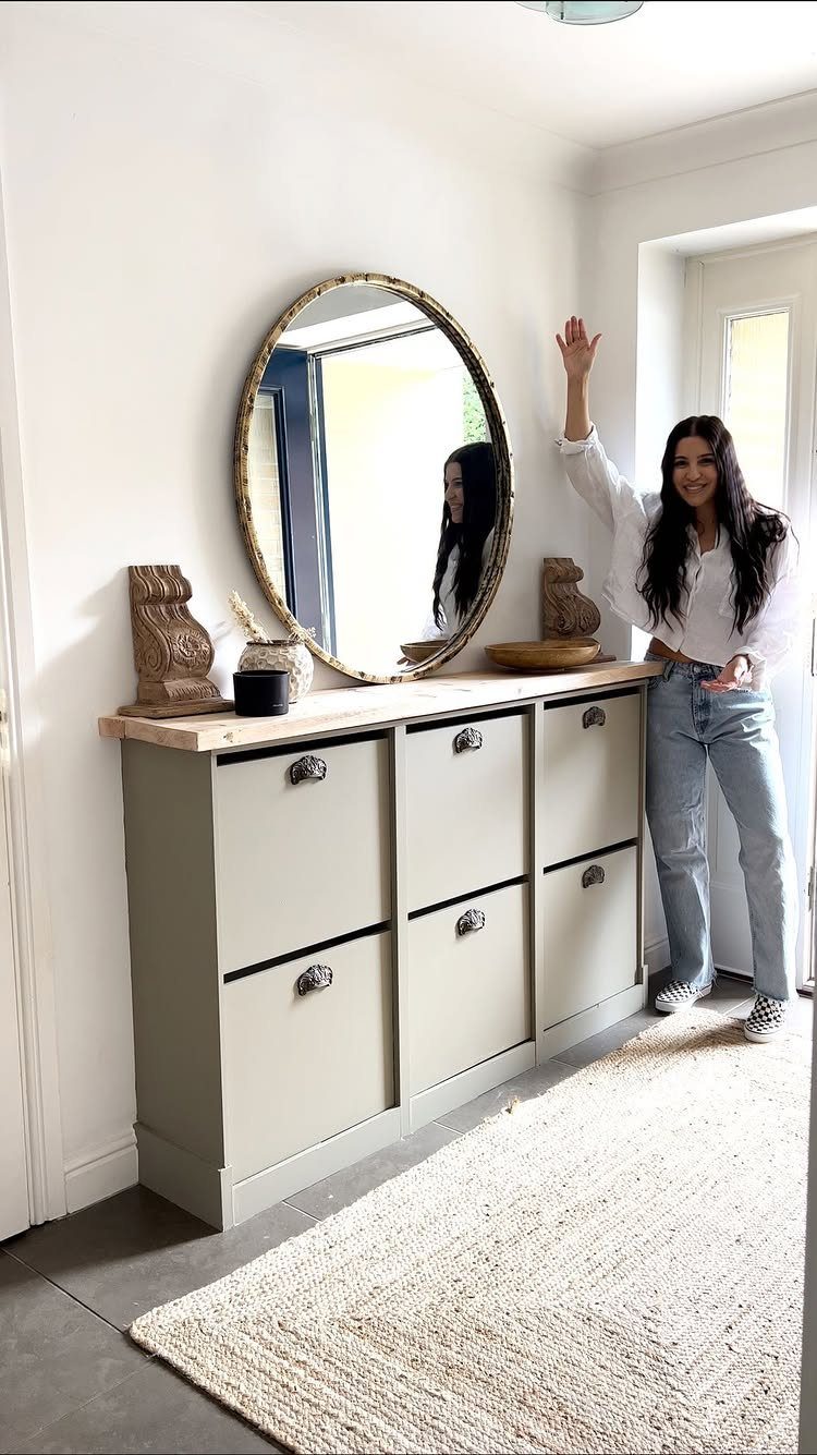 Modified light grey shoe cabinet with wooden top and oval mirror in entryway