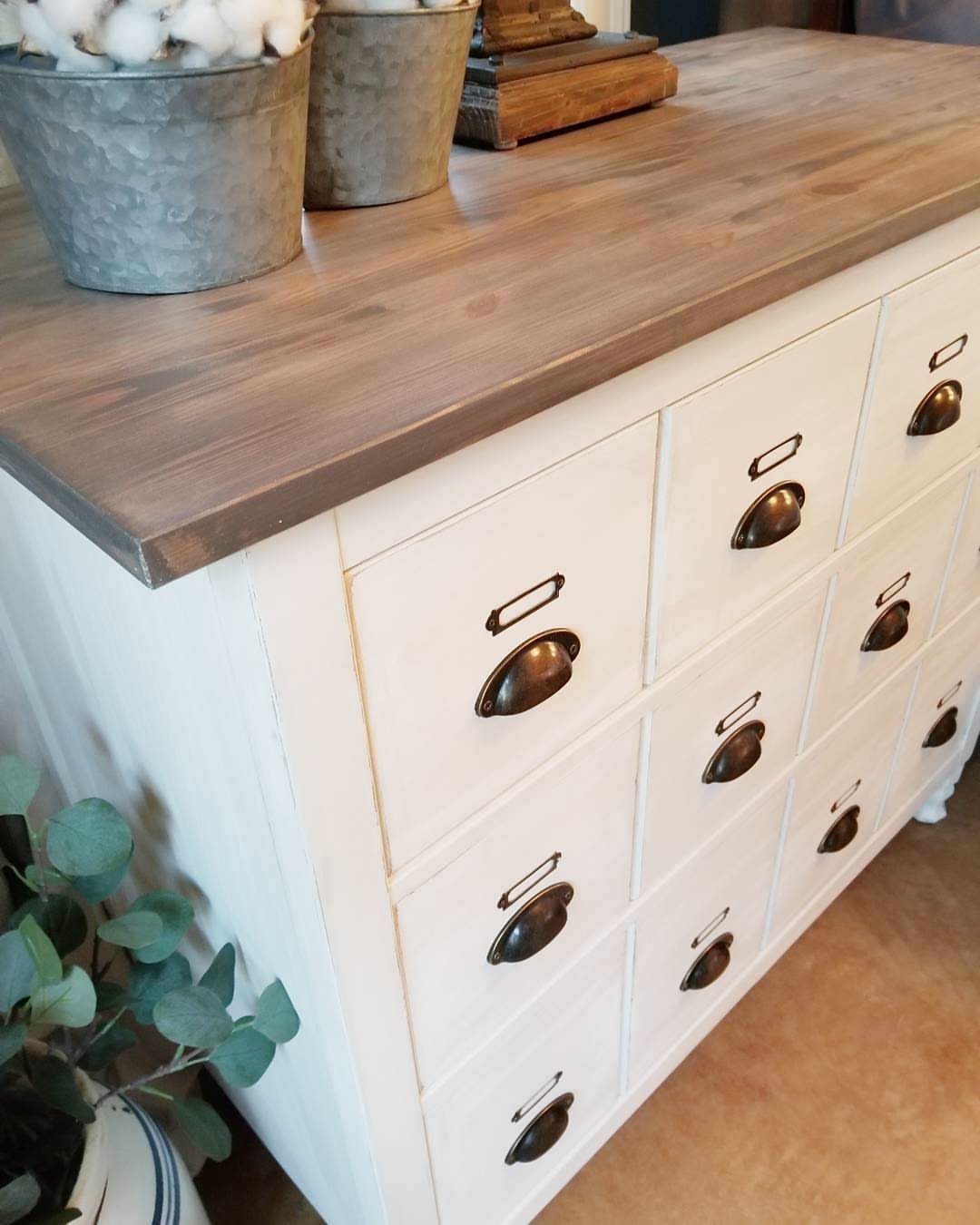 White wooden dresser with brown top and dark metal cup drawer handles