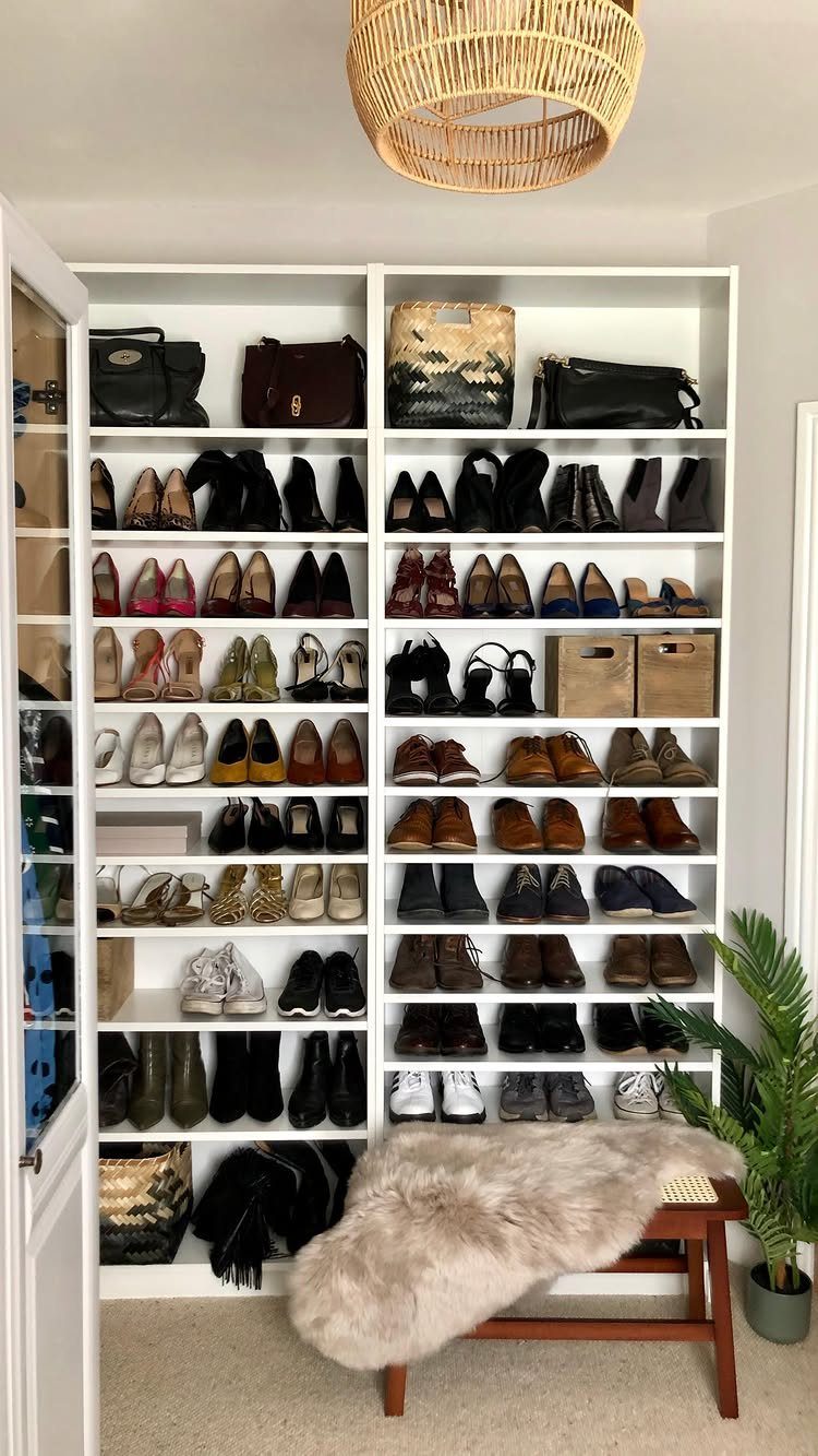 White BILLY bookcases filled with organized shoes and bags next to a fur bench.