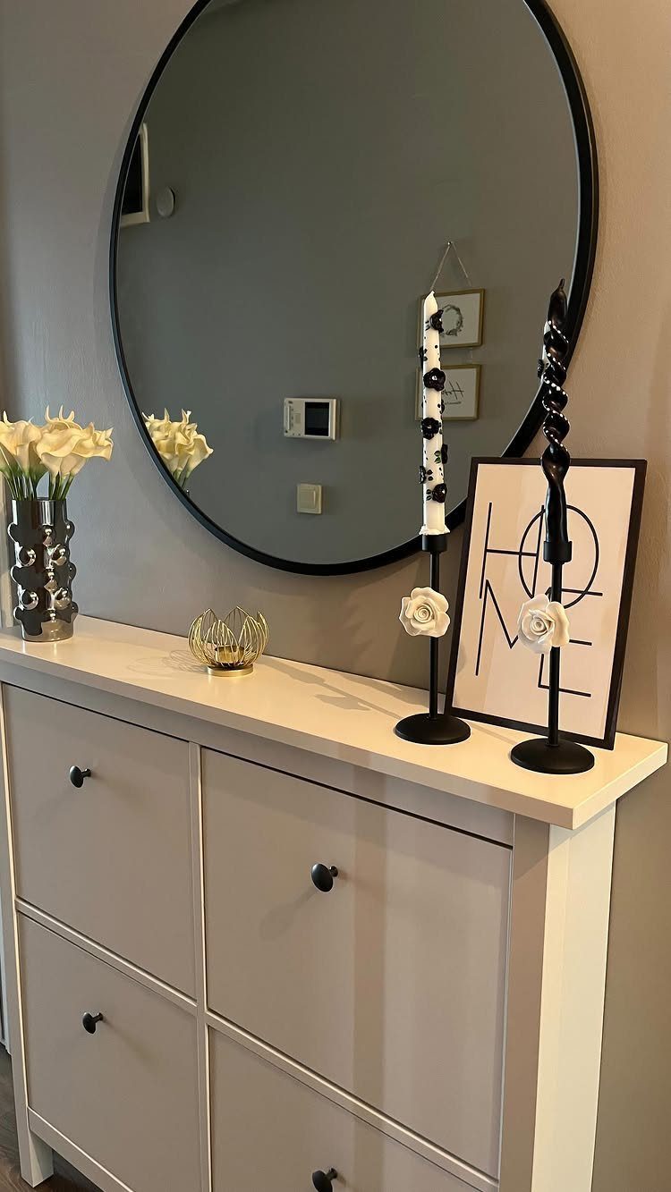 White IKEA shoe cabinet console table with a round mirror and home decor.