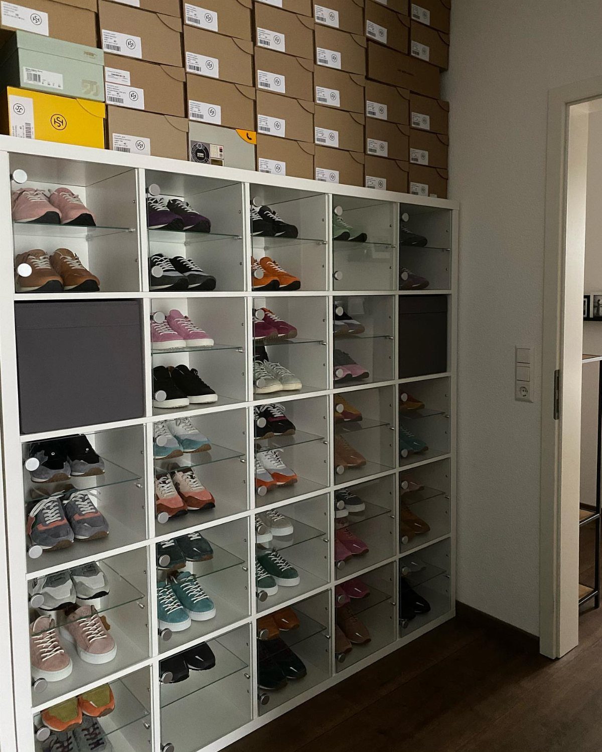 White KALLAX shelving unit used as a shoe cubby for a large collection.