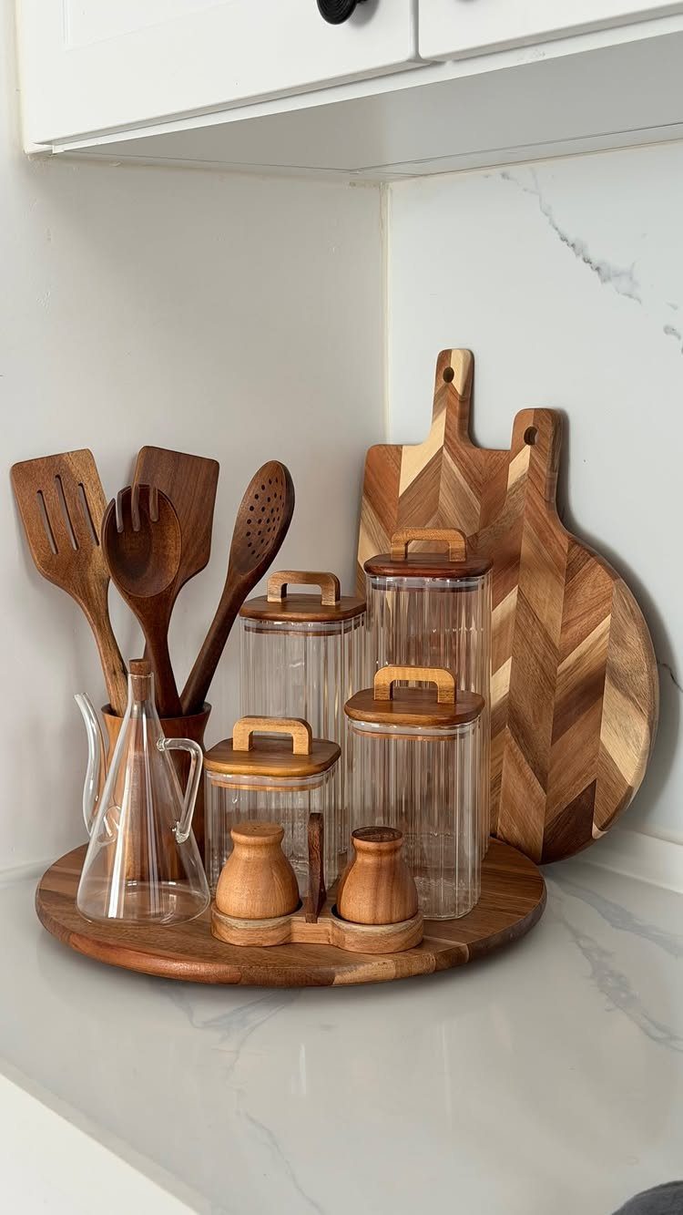 Wooden lazy Susan turntable holding glass jars and cooking utensils on a kitchen counter.