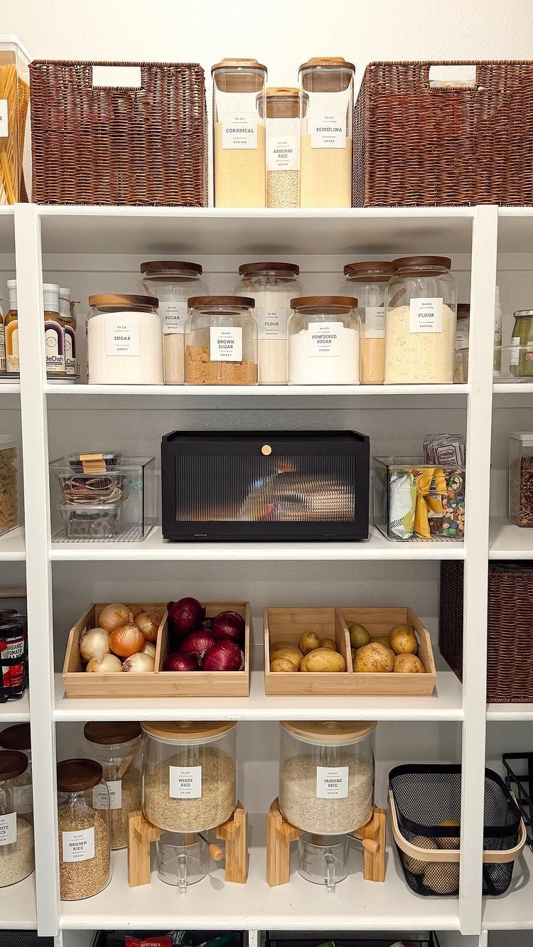 White pantry shelves with wicker baskets, glass jars, and wooden vegetable crates.