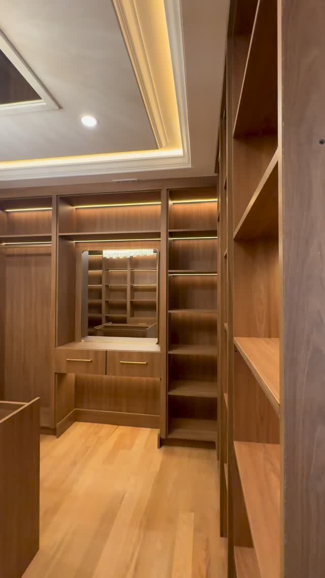 Wooden walk-in closet with integrated LED strip lighting and open shelving units.